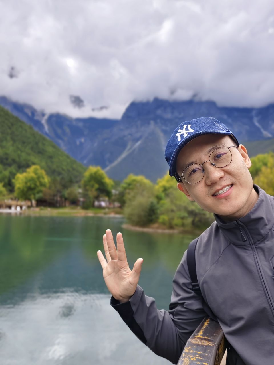 蓝月谷湖畔云雾雪山前挥手留影