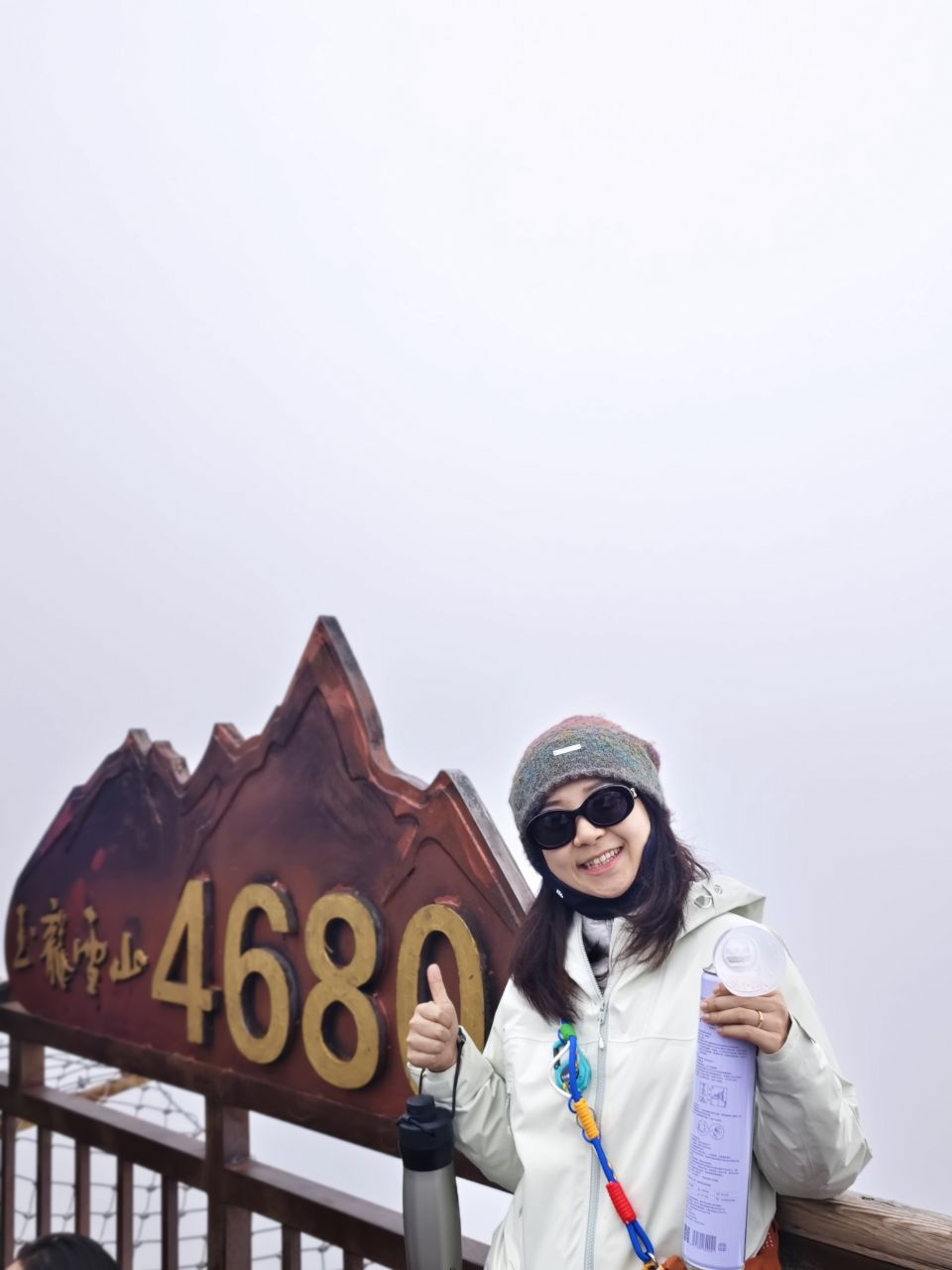 玉龙雪山4680米标志前拿着氧气的游客留影