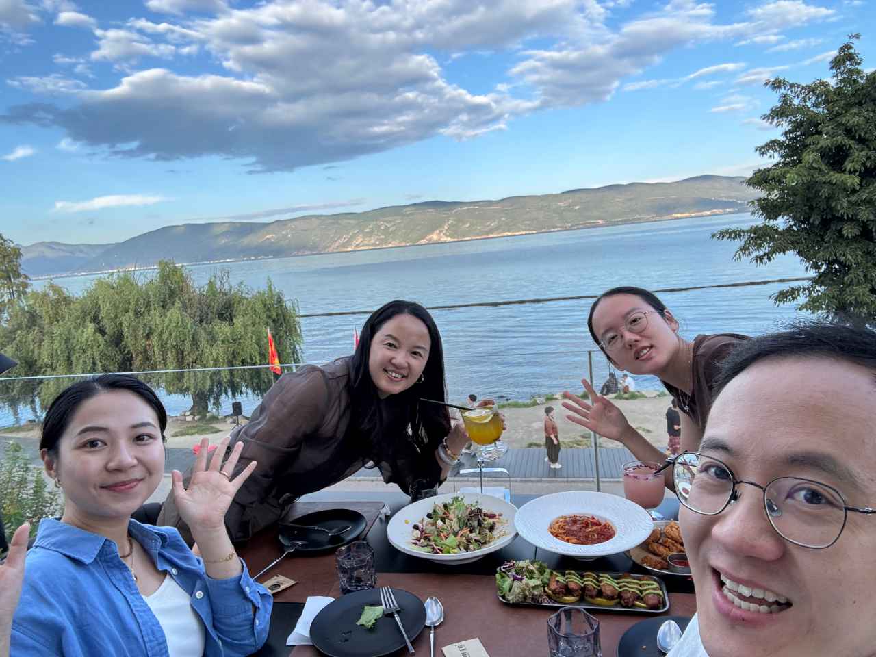 四人在海景餐厅举杯晚餐的自拍合影