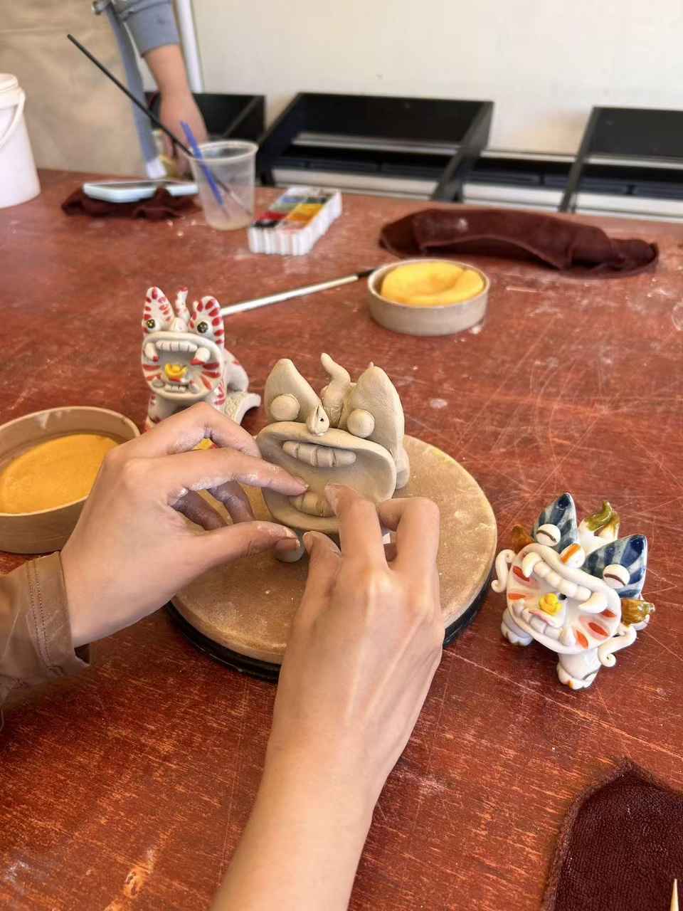 双手正在塑形一只泥塑瓦猫