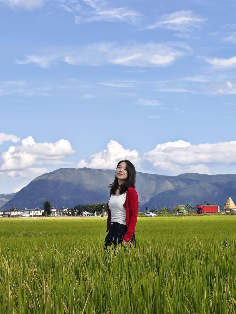 女生站在稻田里侧头微笑,风从稻穗间吹过