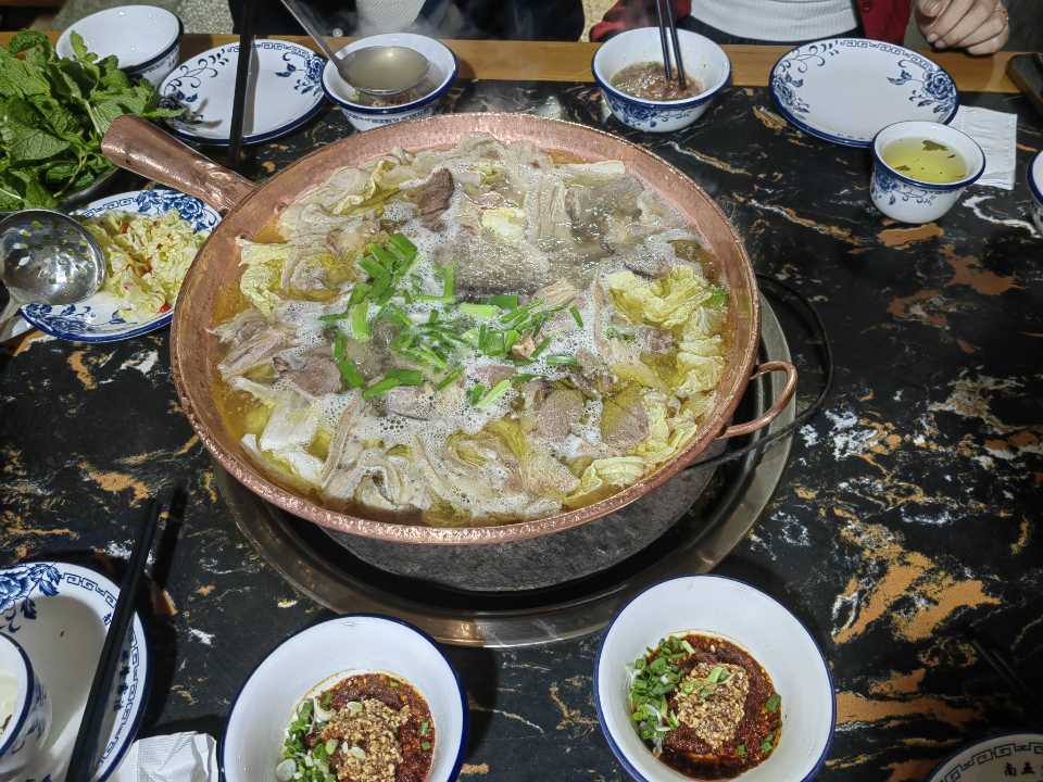铜瓢牛肉火锅:铜锅里冒着热气的清汤牛肉与蘸料